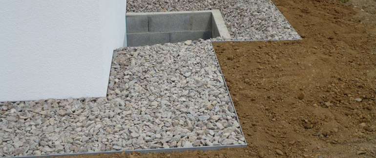 une bande de propreté : de la pierre concassée ou de rivière sur 600 mm (24 pouces) tout autour de la maison. Cette mesure limitera par le fait même les éclaboussures sur les murs et réduira les risques que l'eau et l'humidité n'atteignent les fondations.